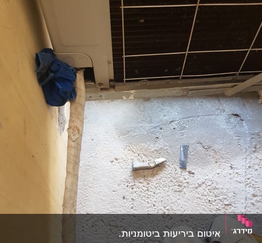 אדם עובד על איטום ליד מזגן עם כלים